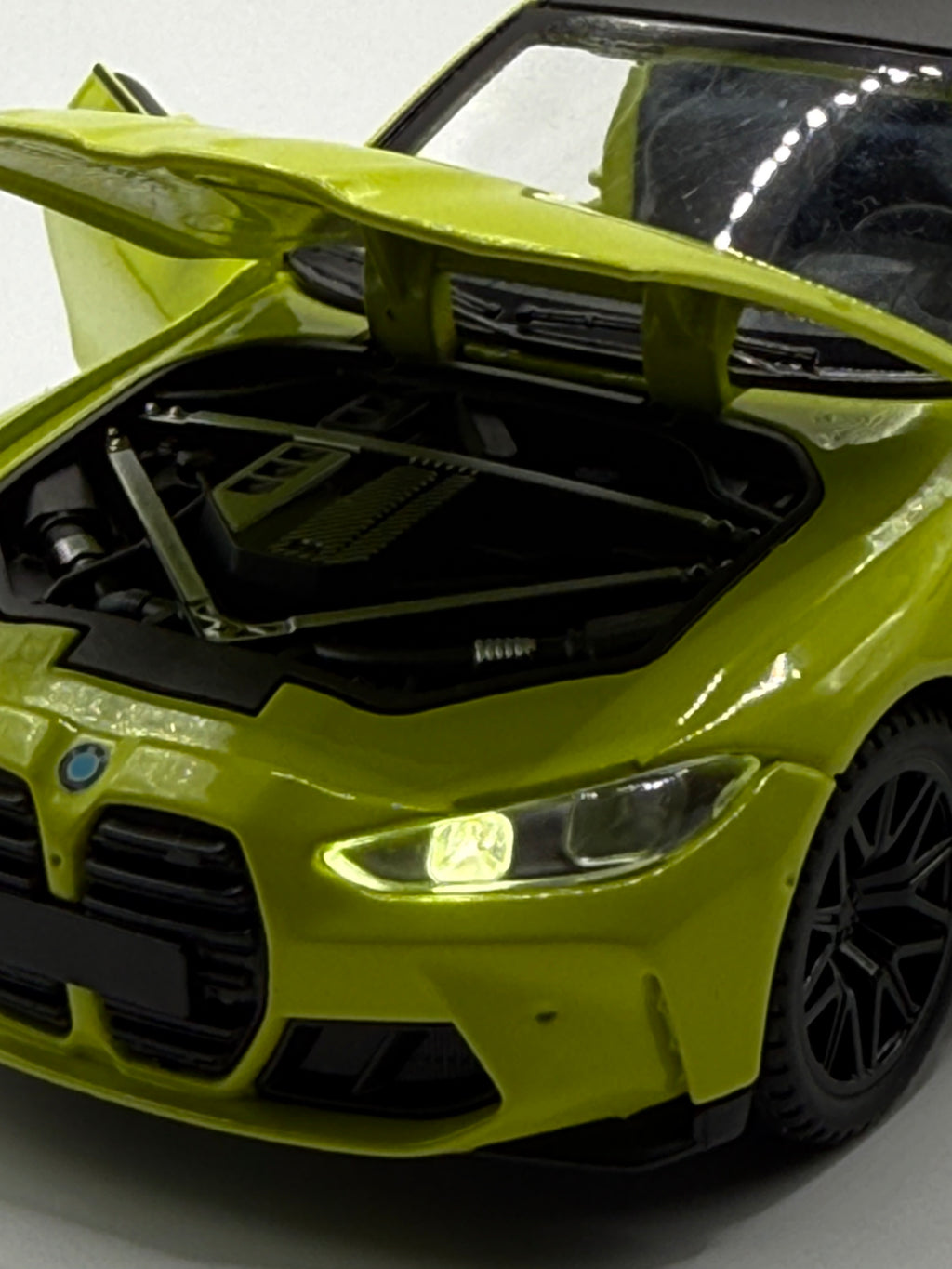 Close-up of 1/32 BMW M4 diecast car with opening doors and hood, showing the detailed interior dashboard and engine bay.