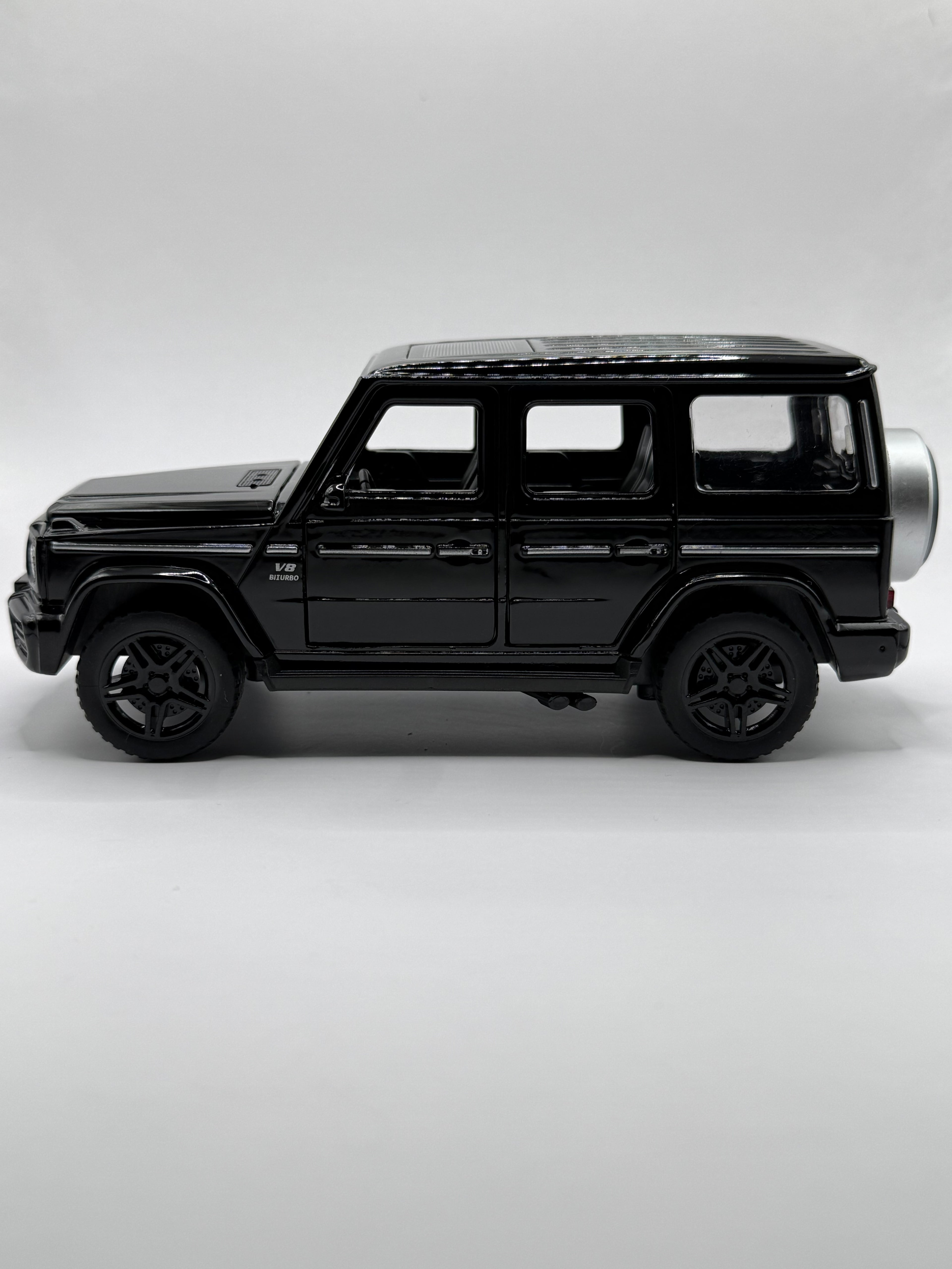 Side profile view of black 1:32 Mercedes G63 scale model car showing wheels and side trim.